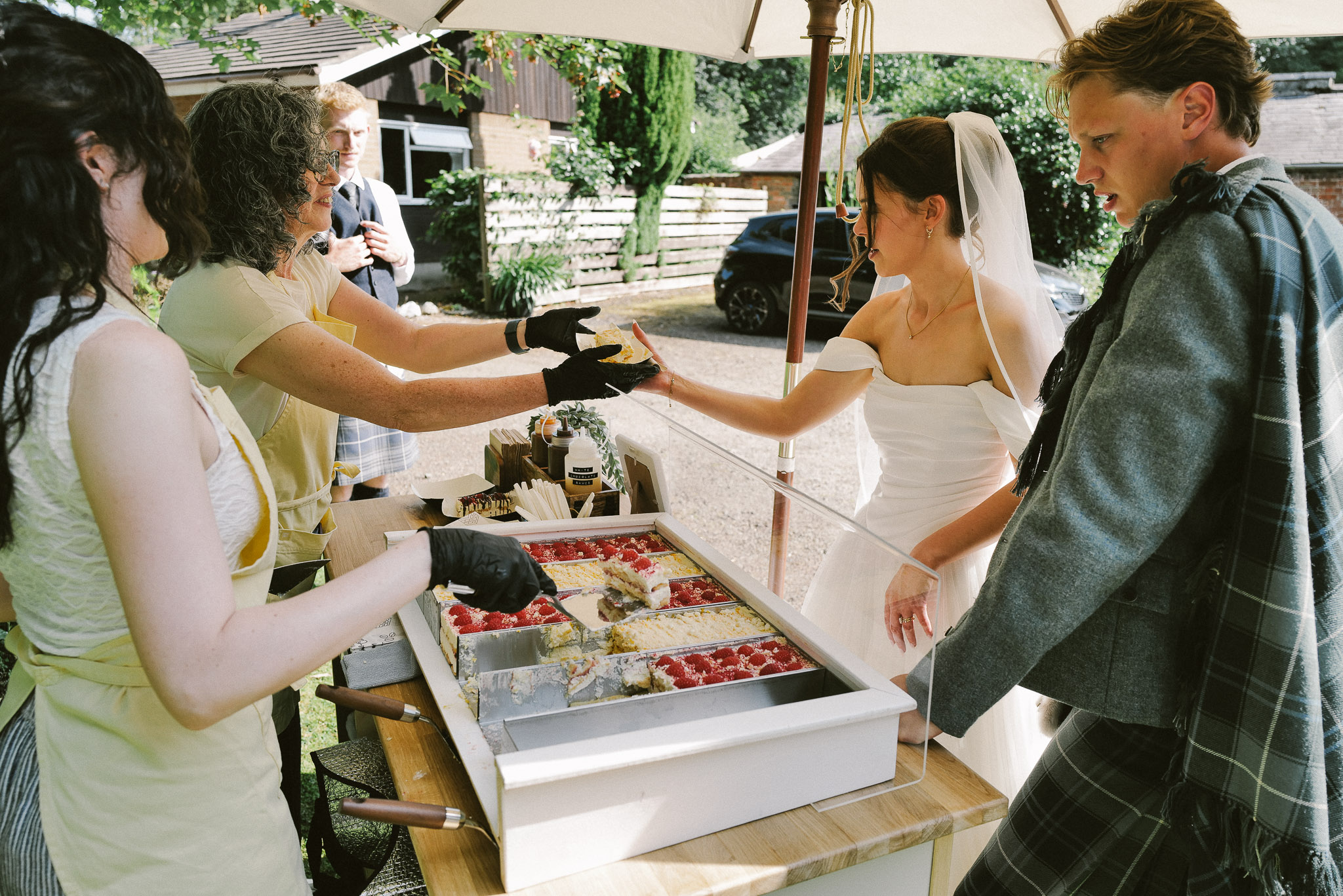 A newly married couple being handed fresh tiramisu from the cart